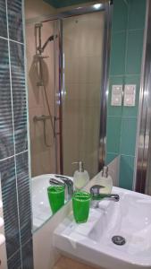 Un baño con lavabo con dos tazas verdes. en Forsycja en Gdansk