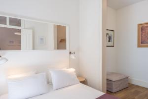um quarto com uma cama branca e um espelho em The 3 Sisters Lisbon em Lisboa