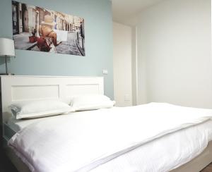 Un dormitorio con una cama blanca con un cuadro en la pared. en Downtown Tirana Apartments, en Tirana