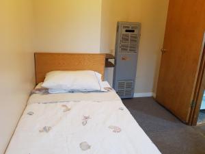 a small bedroom with a bed and an air conditioner at Hat Motel in Medicine Hat