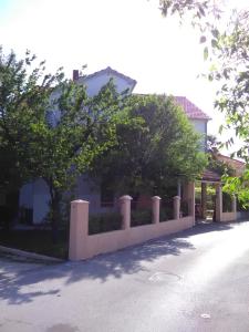 a fence in front of a house with trees at Apartment Ružica in Sukošan
