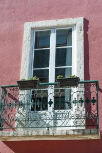 a window on a pink building with potted plants on it at The 3 Sisters Lisbon in Lisbon