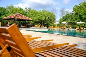 a swimming pool with wooden chairs and a swimming pool at Amaya Lake Dambulla in Sigiriya