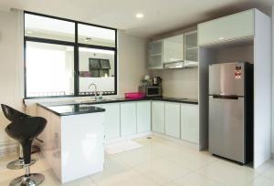 a kitchen with white cabinets and a stainless steel refrigerator at Holiday Homes At Samsuria Resort in Kampung Sungai Ular