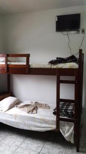 a bunk bed in a room with a tv on a wall at Pousada Catavento in Piraí