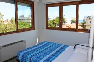 a bedroom with a bed and three windows at Hotel Saint Tropez in Riccione