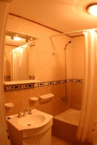 a bathroom with a sink and a tub and a shower at Hostel de Las Manos in El Calafate