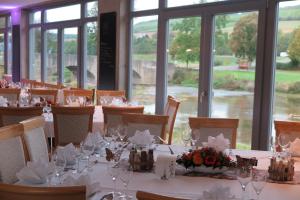 ein Esszimmer mit Tischen, weißen Tischdecken und Blumen in der Unterkunft Landgasthof zum Hirschen in Tauberrettersheim