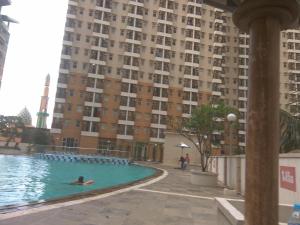 a person swimming in a pool in front of a tall building at DSV Margonda Residen 2 Apartment in Depok