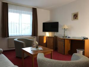 a hotel room with a couch and a television at gut-Hotel Pommernhotel Barth in Barth