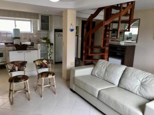 uma sala de estar com um sofá branco e cadeiras em Linda Cobertura Caiobá, amplo terraço com churrasqueira, e linda vista na Av Atlântica, Edificio Frente Mar em Caiobá