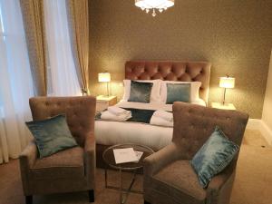 um quarto com uma cama e 2 cadeiras em The Devon Court em Torquay