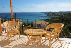 three chairs and a table on a balcony with the ocean at Alkioni Studios in Trapezaki