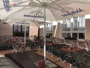 a restaurant with tables and chairs under umbrellas at Hotel Korfu in Geiselhöring