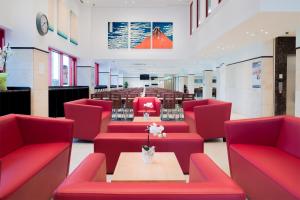 - une salle d'attente avec des chaises rouges et une table dans l'établissement Toyoko Inn Frankfurt am Main Hauptbahnhof, à Francfort-sur-le-Main