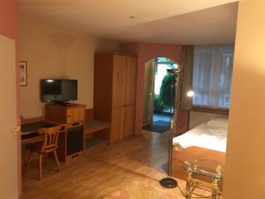 a bedroom with a bed and a desk with a television at Hotel Korfu in Geiselhöring