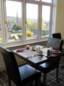 a dining room table with chairs and a large window at The Knowe Guest House in Callander