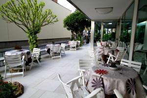 d'une terrasse avec des tables, des chaises blanches et un lecteur de table. dans l'établissement Hotel Capri, à Bellaria-Igea Marina