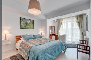 a white bedroom with a bed and a window at Bucharest Airport Suites & Villas in Otopeni
