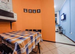 a room with an orange wall with a table and a tv at Rooms on Pirogova in Saint Petersburg