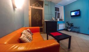 a living room with an orange couch and a table at Rooms on Pirogova in Saint Petersburg
