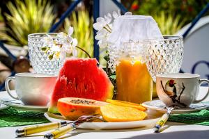 a table topped with cups and plates of fruit at Garapua Praia Hotel in Garapuá +43 photos