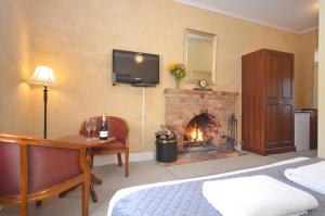 a bedroom with a fireplace and a bed and a desk at Central Springs Inn in Daylesford