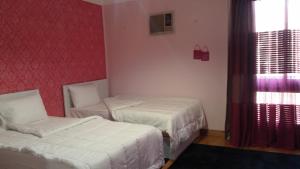 a bedroom with two beds and a red wall at Khayatz Apartment in Cairo