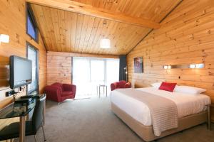 1 dormitorio con 1 cama y TV en una habitación en Lockwood Manor Motel, en New Plymouth