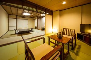 Habitación con mesa, sillas y TV. en Ryochiku Bettei, en Beppu