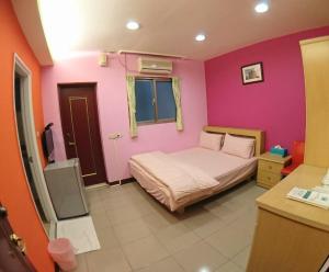 1 dormitorio con cama y pared de color rosa en ZaiXiang en Danshui
