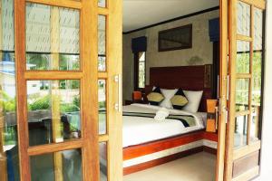 a bedroom with a bed and some glass doors at Wonderland Healing Center in Thongsala