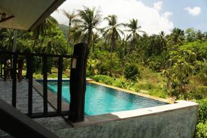 a pool in a resort with palm trees in the background at Wonderland Healing Center in Thongsala