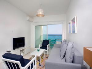 a living room with a couch and a table and a television at On The Beach Penthouse by TrulyCyprus in Limassol