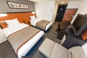 a hotel room with two beds and a flat screen tv at HOTEL MYSTAYS Sakaisuji Honmachi in Osaka