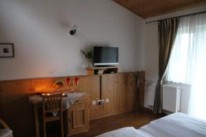een slaapkamer met een bureau en een tv aan de muur bij Weingut Schatz in Heimschuh