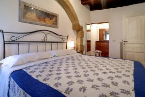 een slaapkamer met een bed met een blauwe en witte quilt bij Casetta Nella Fratta in Pitigliano