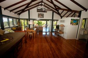 ein Wohnzimmer mit Holzböden und ein Esszimmer in der Unterkunft Bedarra Beach House in Bedarra Island