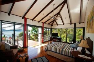 a bedroom with a bed and large windows at Bedarra Beach House in Bedarra Island