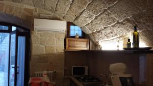 cocina con pared de piedra, fogones y ventana en Cuore di Pietra B&B, en Polignano a Mare