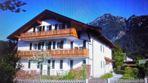 a large white building with a wooden roof at Apartment Rudi in Garmisch-Partenkirchen