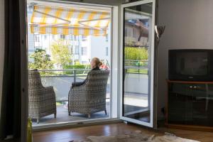 a woman sitting in a chair on a balcony at Konstanz nähe, ruhiges 4-Zim-Wohnung bis 8 Personen in Kreuzlingen
