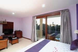a bedroom with a bed and a balcony with a television at Melasa House in Senggigi  +8 photos