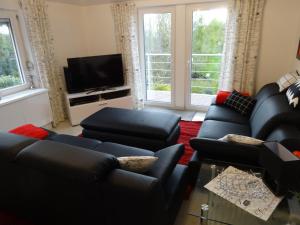 ein Wohnzimmer mit schwarzen Ledermöbeln und einem Flachbild-TV in der Unterkunft Ferienwohnung Spier in Ottenstein