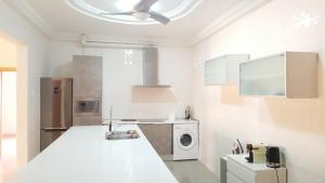 a white kitchen with a sink and a dishwasher at Muntala's Guest House in Hohoe