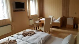 フランチシュコヴィ・ラーズニェにあるPension U Dubuのベッド、テーブル、椅子が備わる客室です。