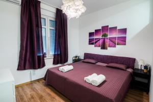 - une chambre avec un lit violet et 2 serviettes dans l'établissement CheckBelgradeApartment- City Center, à Belgrade
