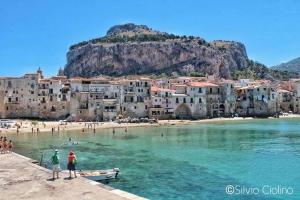 a group of people on a beach with a mountain at Mandralisca Garden in Cefalù