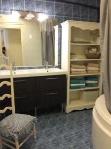 baño con lavabo, espejo y silla en La Maison Rouge en Chinon