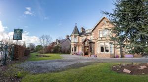 una casa vieja con un cartel delante en Chrialdon House, en Beauly